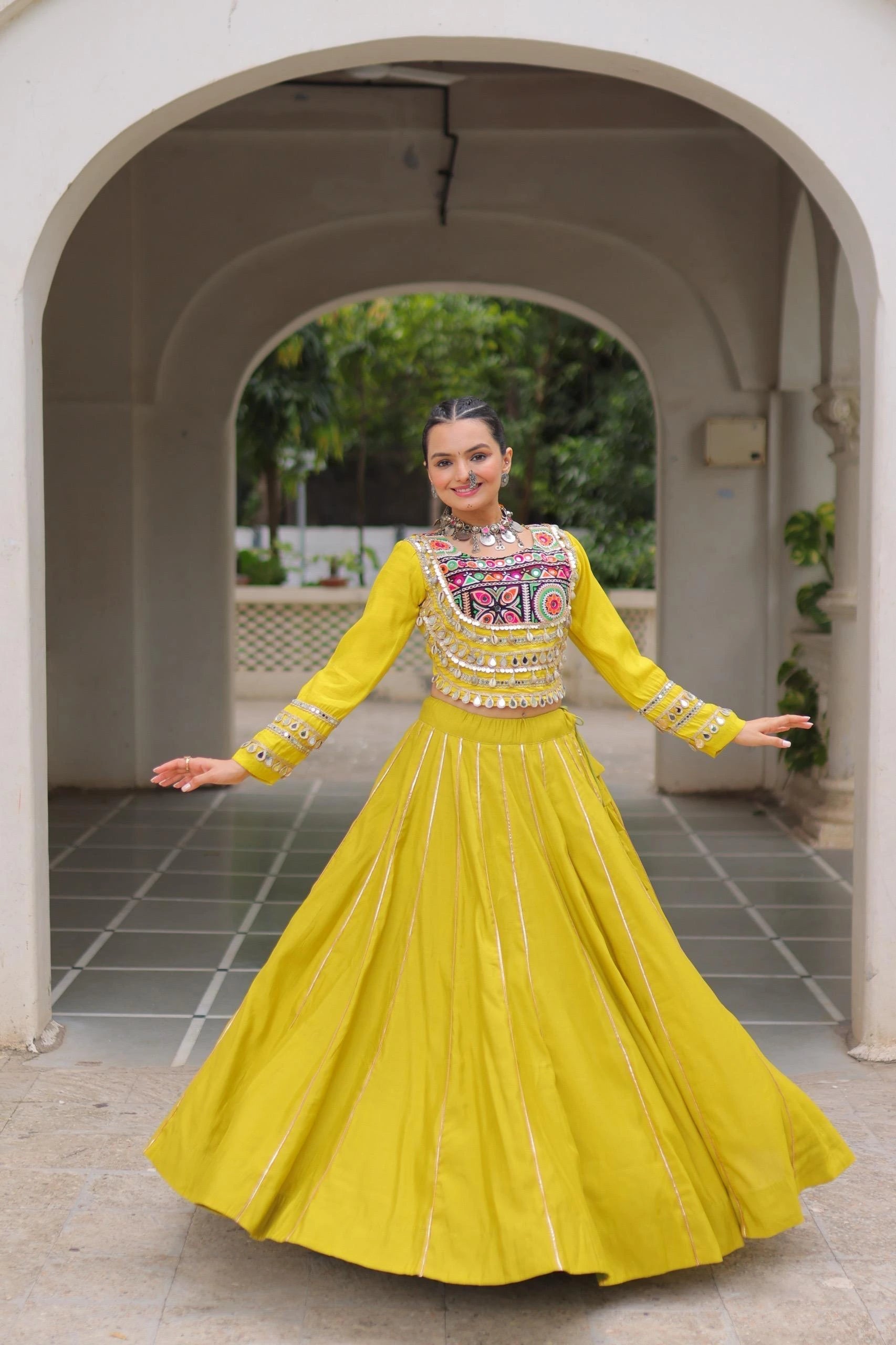Woman in a yellow traditional outfit standing in an archway.